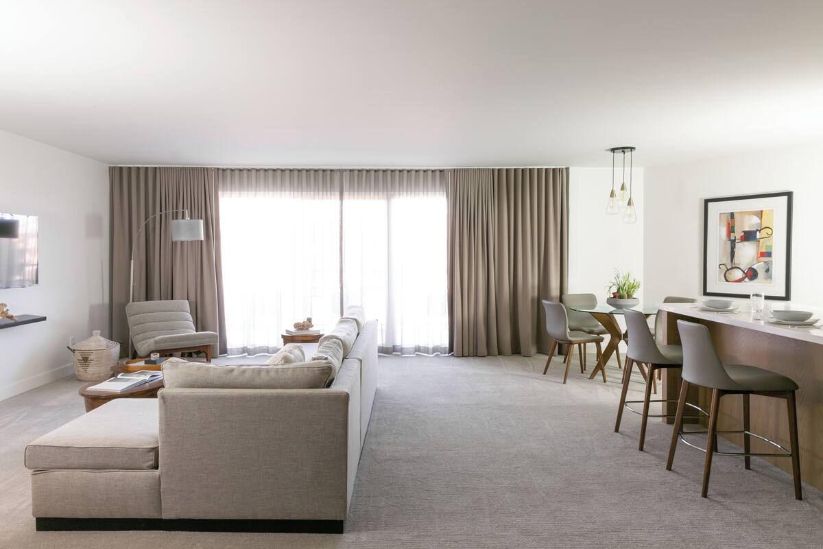 A modern living room with a sofa, dining area, and kitchen counter.