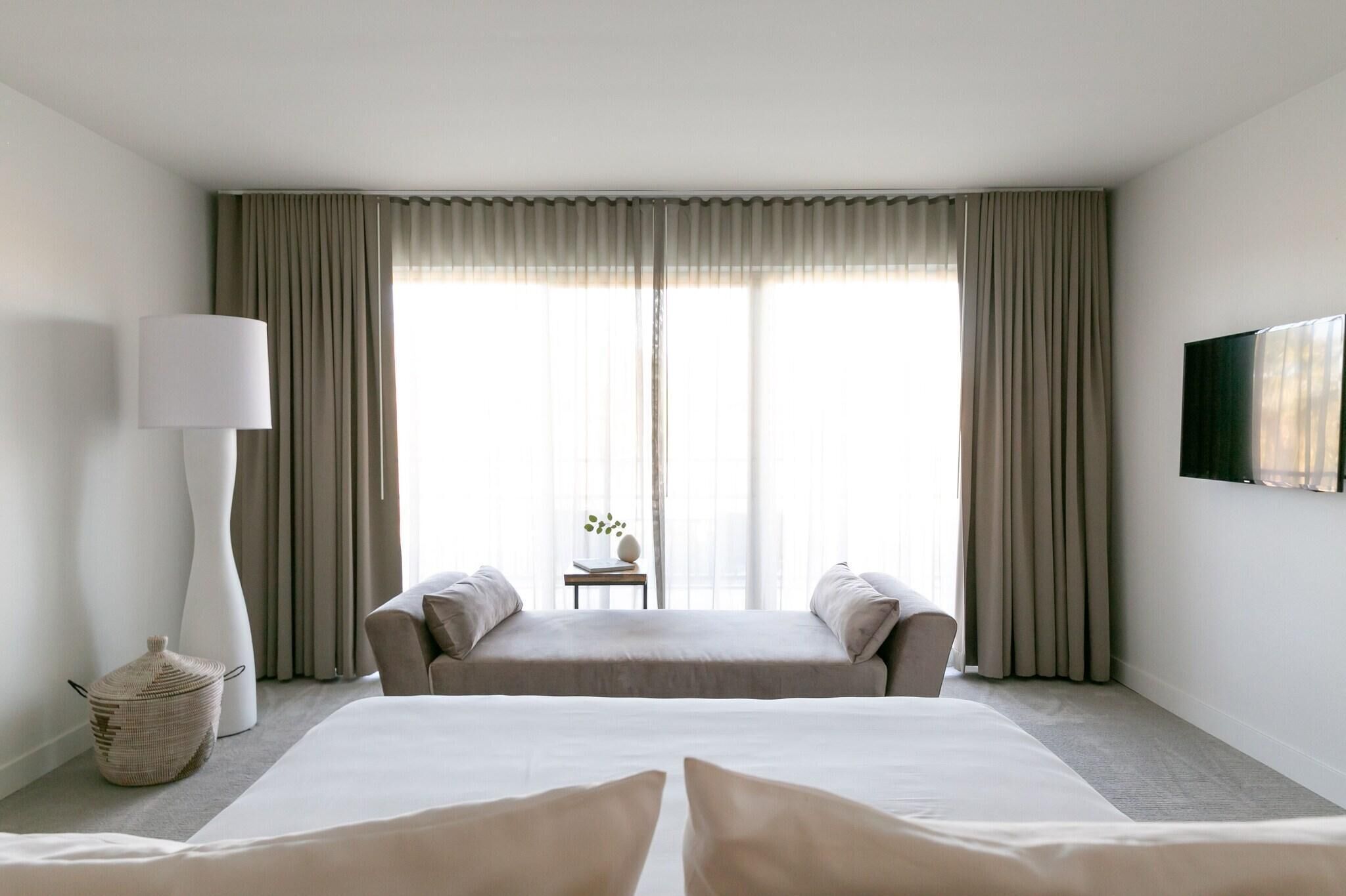 A hotel room with a large bed, two bedside tables, a lamp, and a television on the wall.