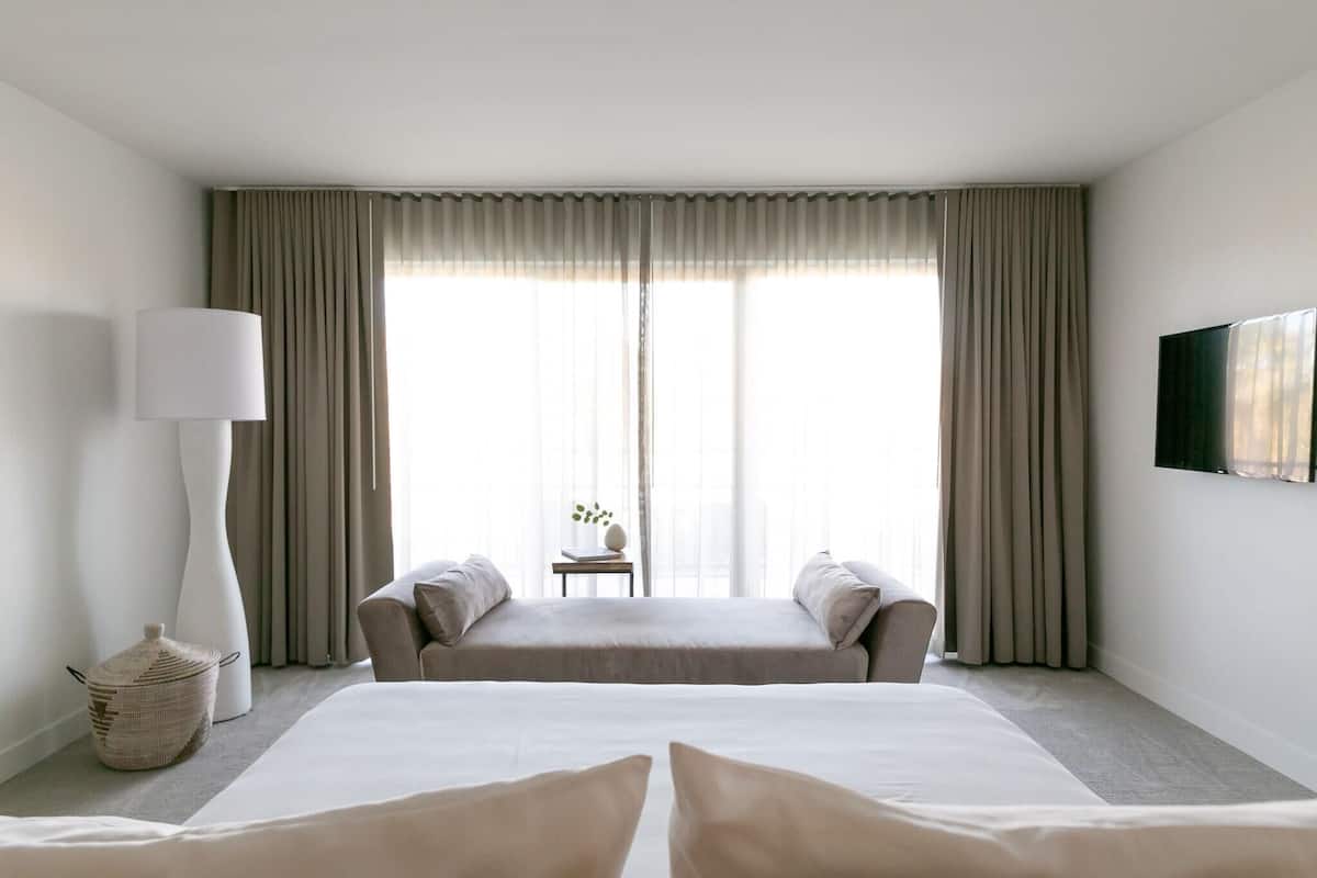 A hotel room with a large bed, two bedside tables, a lamp, and a television on the wall.