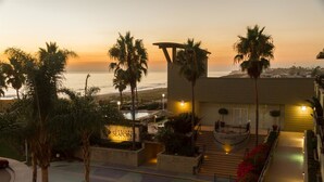 A resort with a pool area, palm trees, and a view of the ocean at sunset. - Carlsbad Seapointe Resort (Carlsbad)