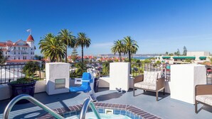 A rooftop pool area with lounge chairs, a hot tub, and a view of the cityscape. - Coronado Beach Resort (Coronado)