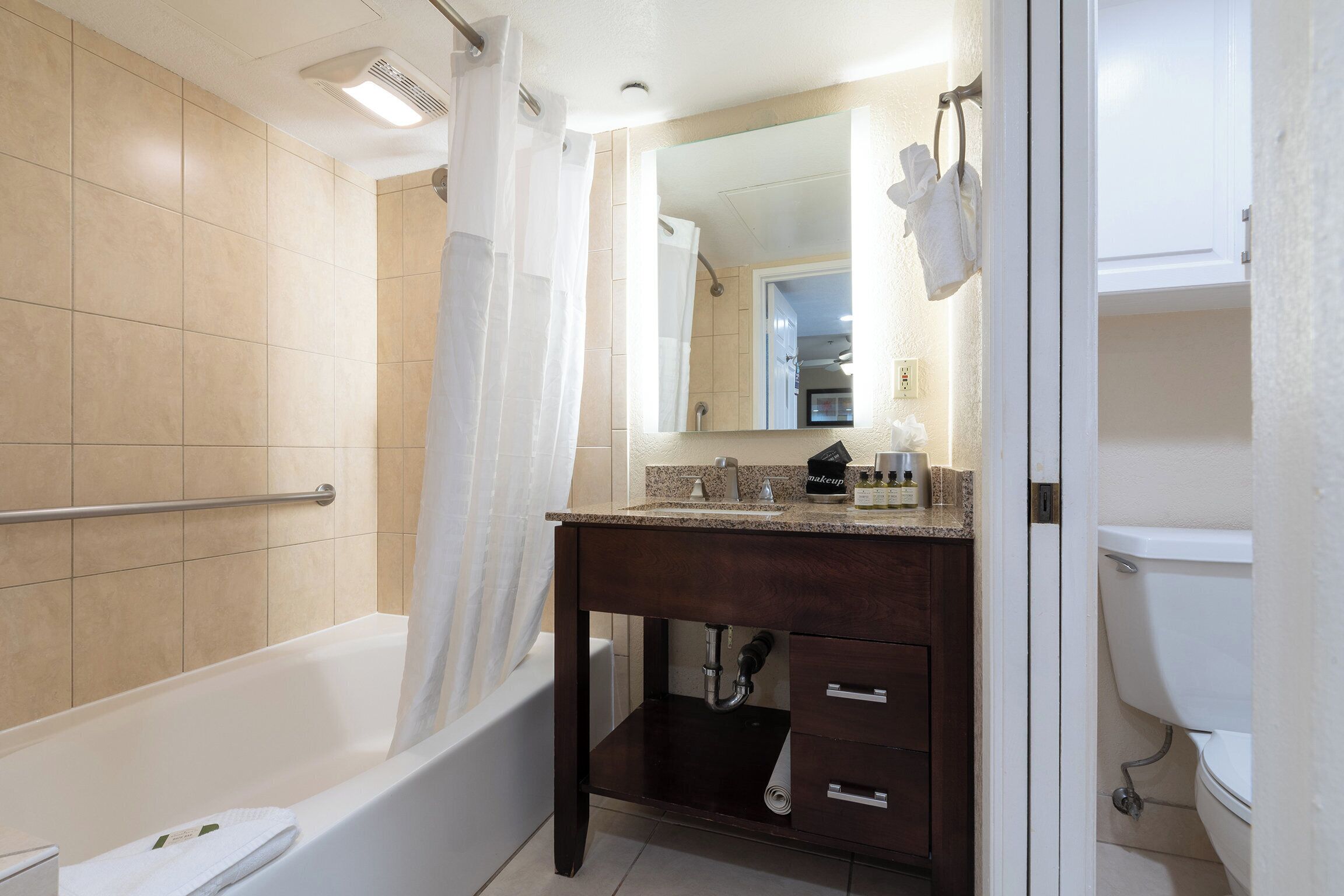 A bathroom with a bathtub, a vanity with a mirror, and a toilet.
