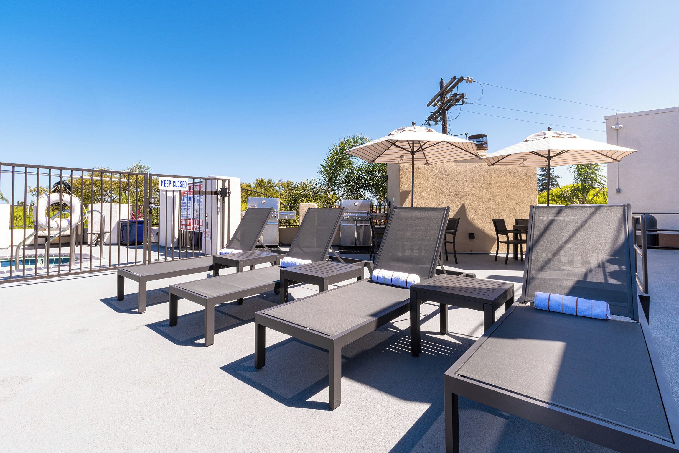Uma área de lounge no terraço com espreguiçadeiras, guarda-sóis e piscina.