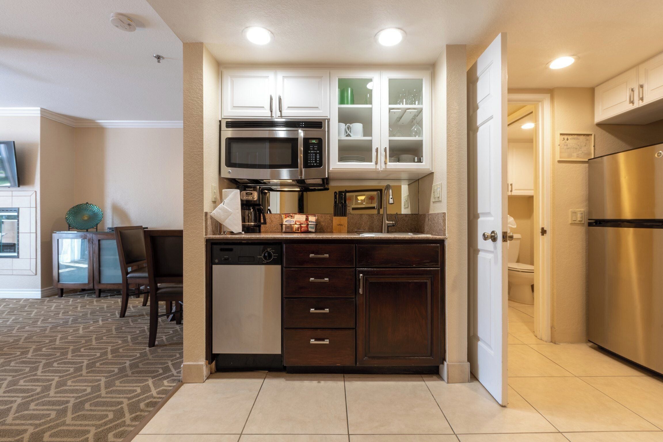 Una cocina compacta con microondas integrado, lavavajillas y refrigerador.