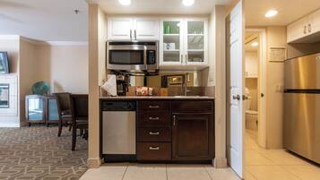Una cocina compacta con microondas integrado, lavavajillas y refrigerador.