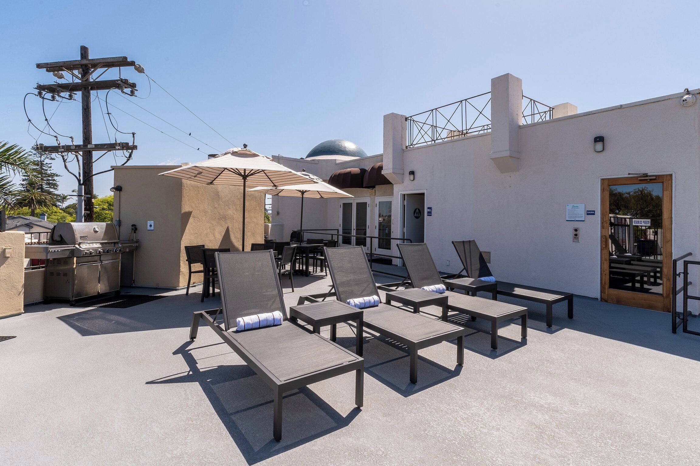 Un espace de détente aménagé sur le toit, avec des fauteuils, un barbecue et des parasols.