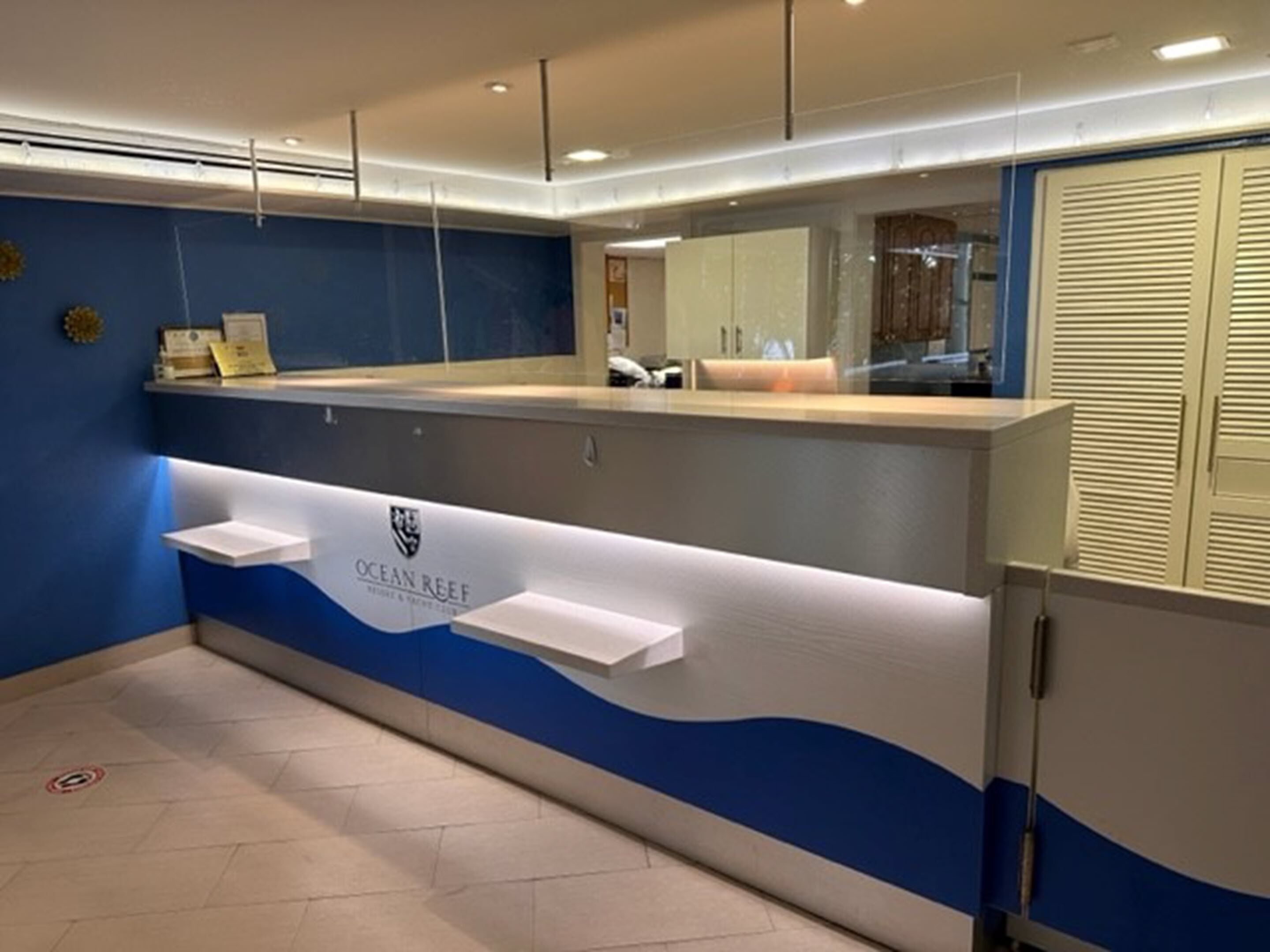 Un área de recepción con una decoración azul y blanca, un mostrador de recepción y una barra.