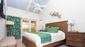 Un dormitorio con cama de madera, ventilador de techo, mesita de noche y ventana con cortinas.