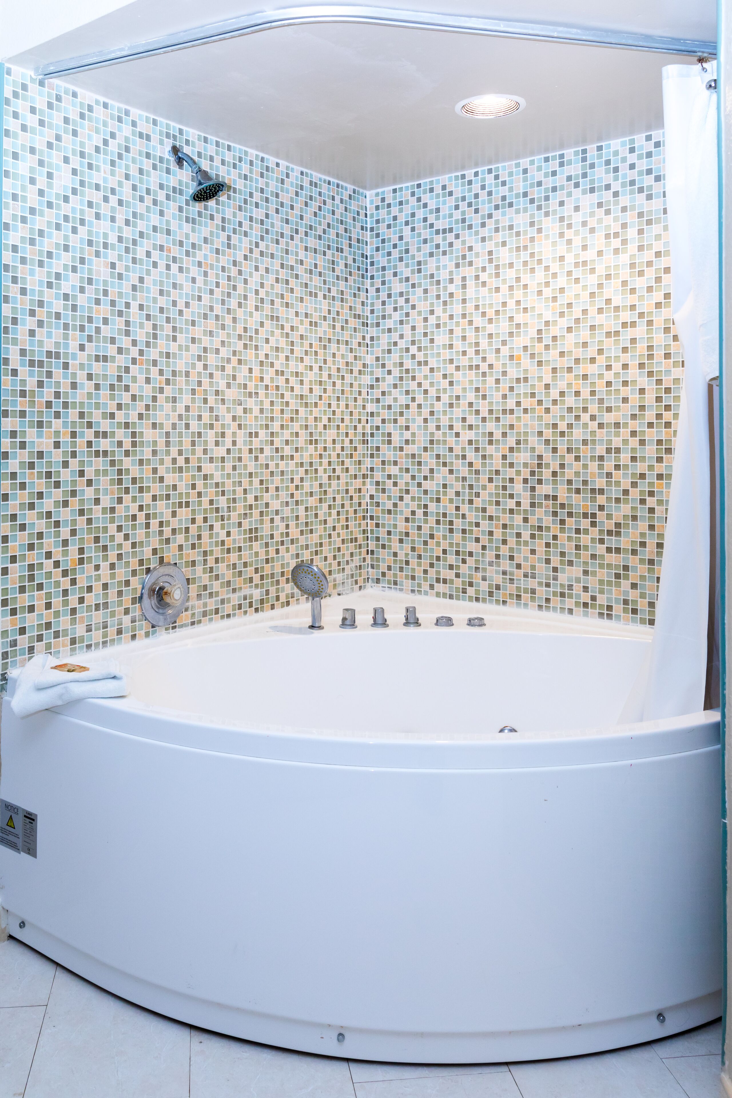 A modern bathroom with a mosaic-tiled shower wall, a freestanding bathtub, and a white shower curtain.