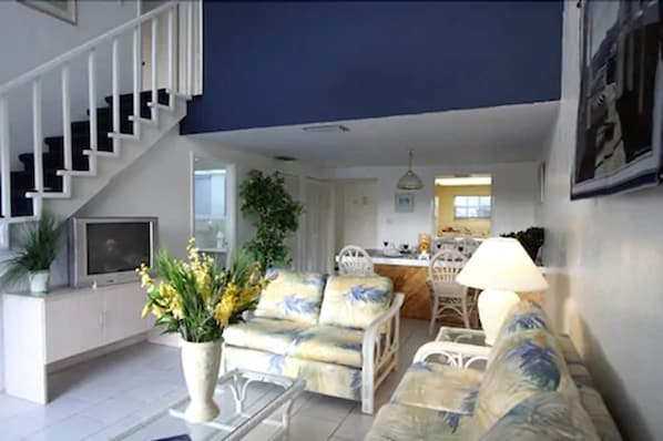 A living room with a sofa, a coffee table, and a TV. There is a staircase leading to another level. - Ocean Reef Yacht Club & Resort (Freeport)