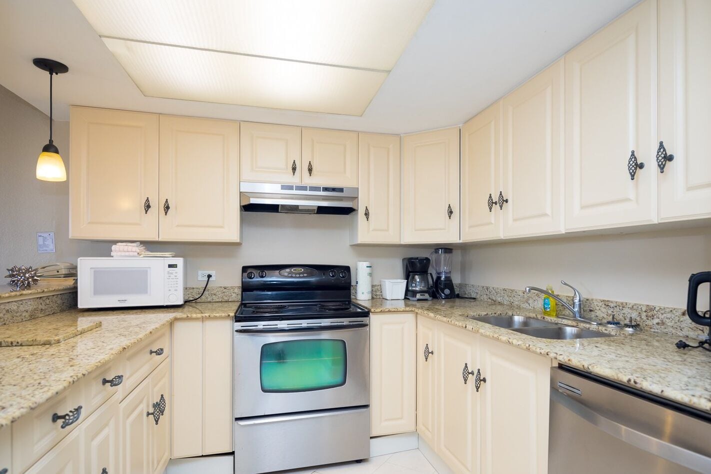 A kitchen with light-colored cabinets, a stainless steel stove, a microwave, and a sink.