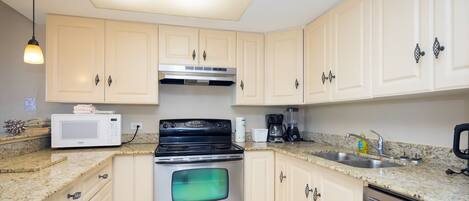A kitchen with light-colored cabinets, a stainless steel stove, a microwave, and a sink.