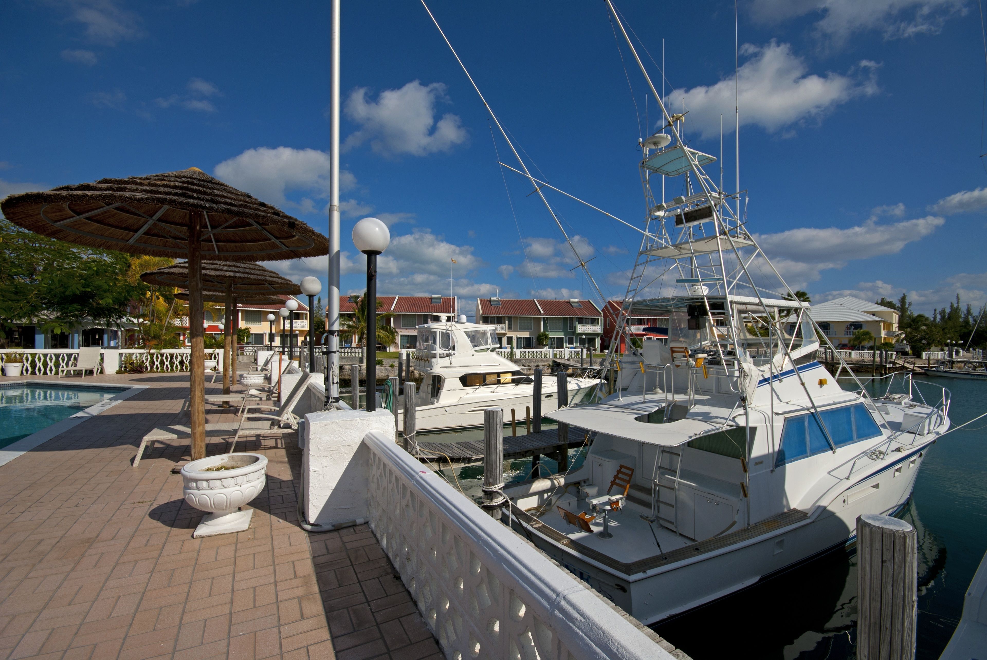 Un puerto deportivo con barcos amarrados, una piscina y un área de estar techada.