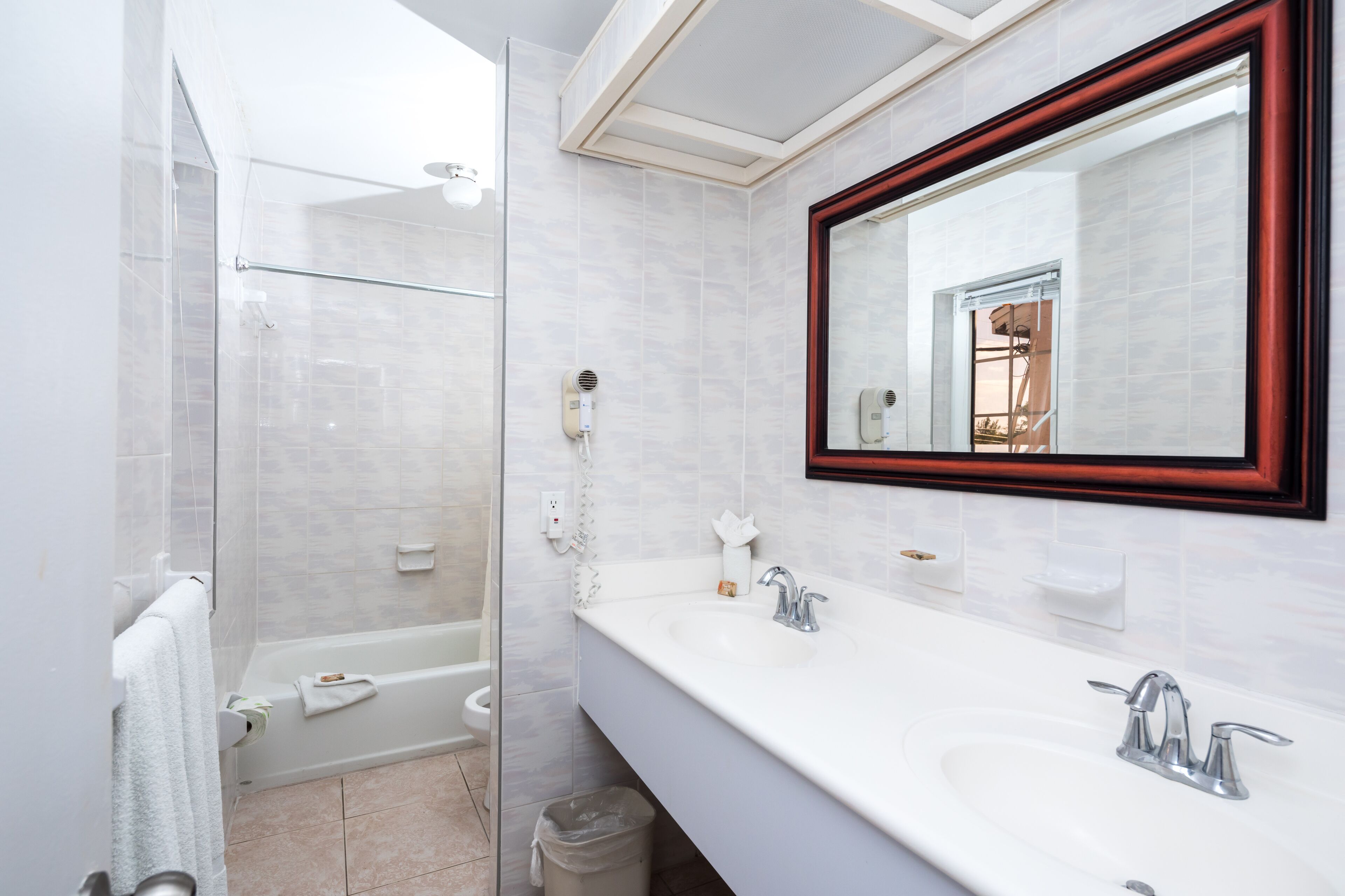 A modern bathroom with a glass shower enclosure, a double sink vanity, and a large mirror with a wooden frame.