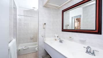 A modern bathroom with a glass shower enclosure, a double sink vanity, and a large mirror with a wooden frame.