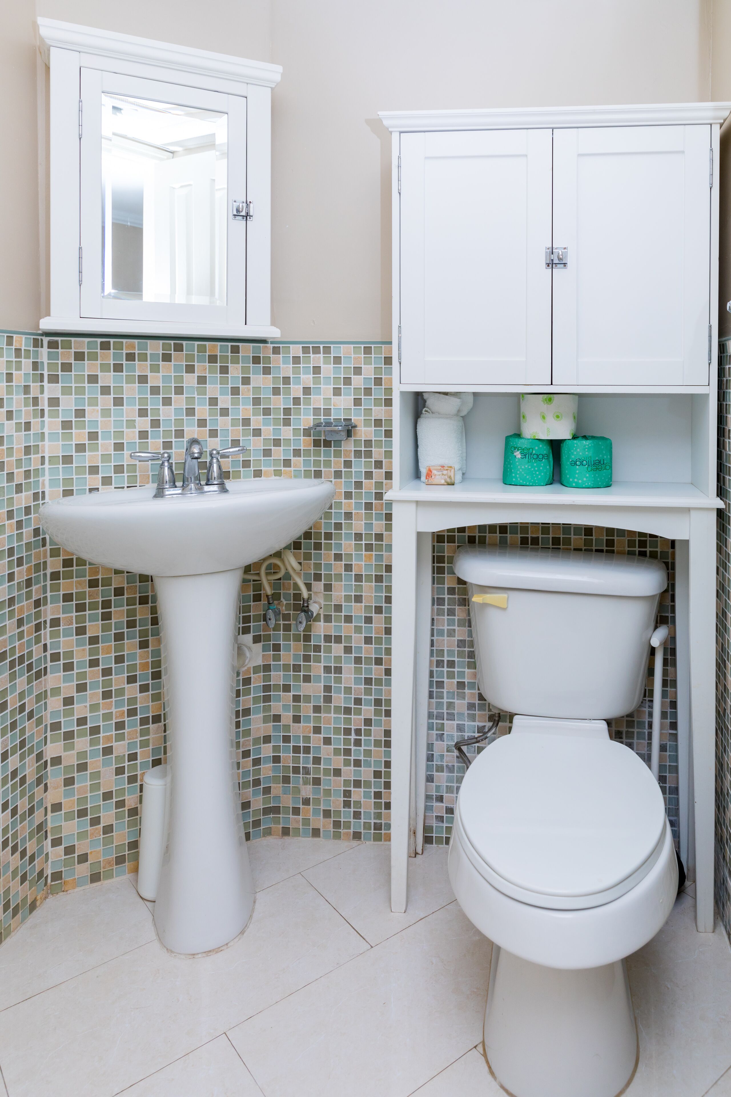 A bathroom with a white sink, toilet, and cabinet.