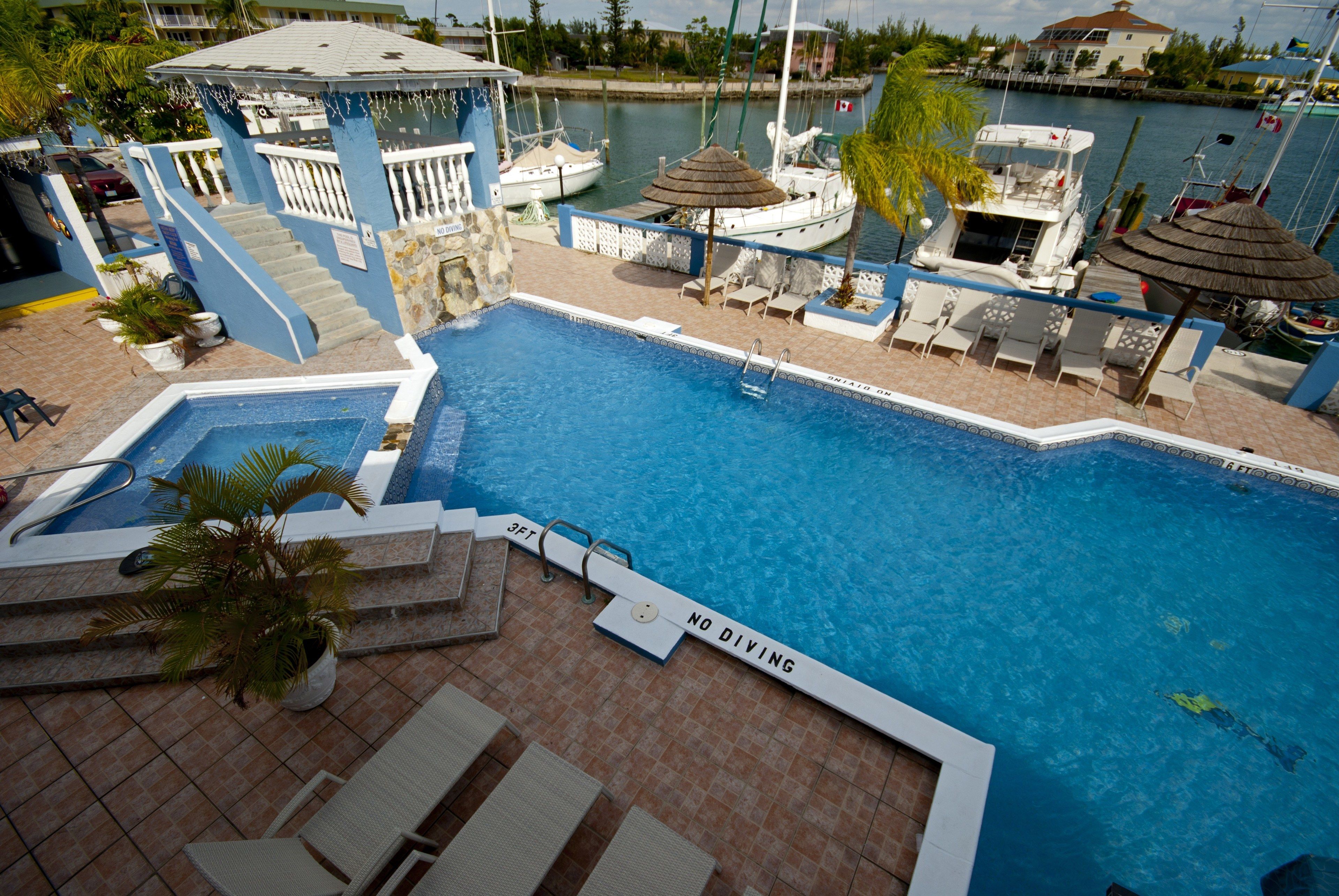 A swimming pool with a 'No Diving' sign, lounge chairs, and a view of the marina.