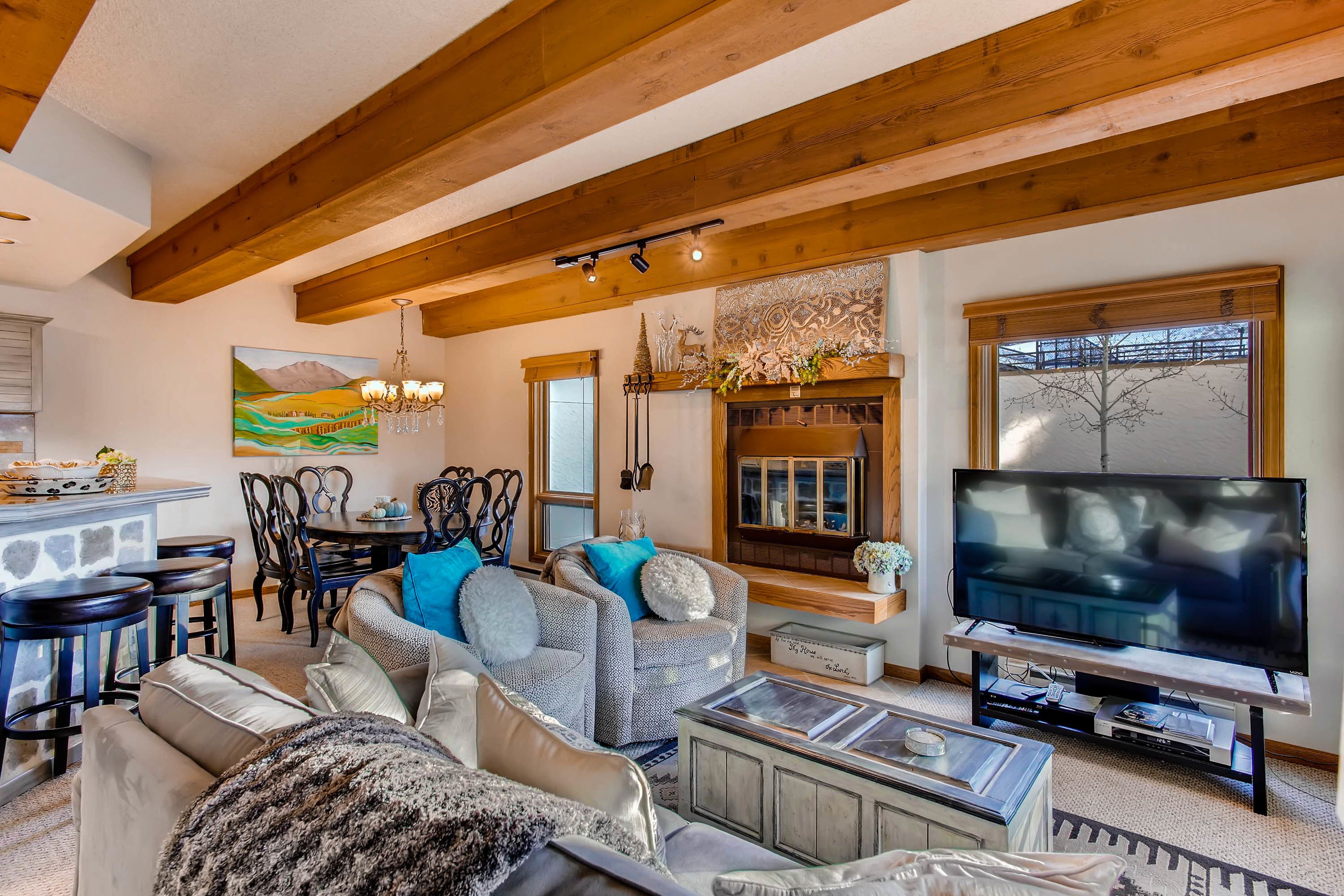 A spacious living room with a fireplace, a large TV, and a dining area with wooden chairs and a table.
