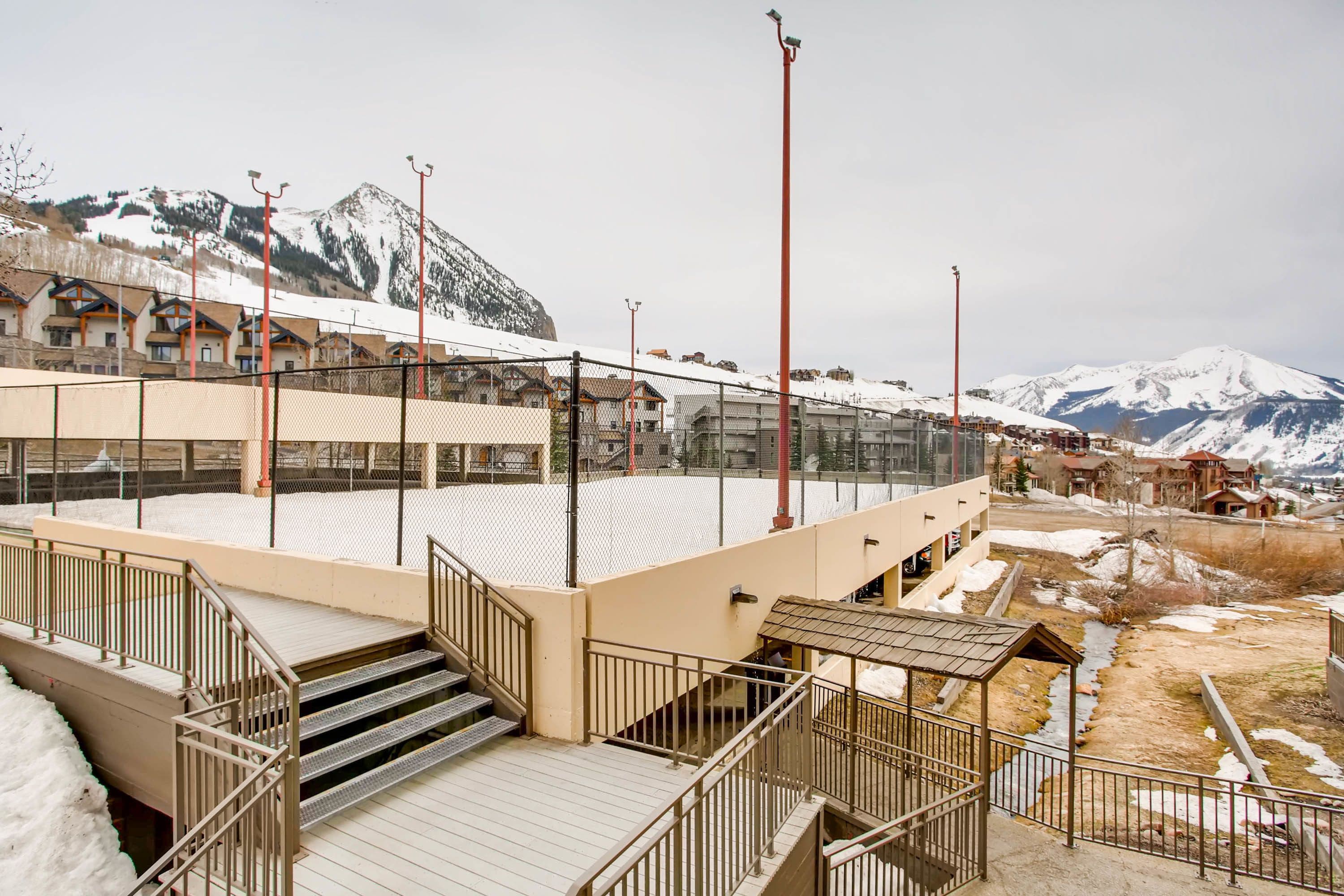 A hotel with a snow-covered roof, a staircase leading to a balcony, and a view of mountains in the background.