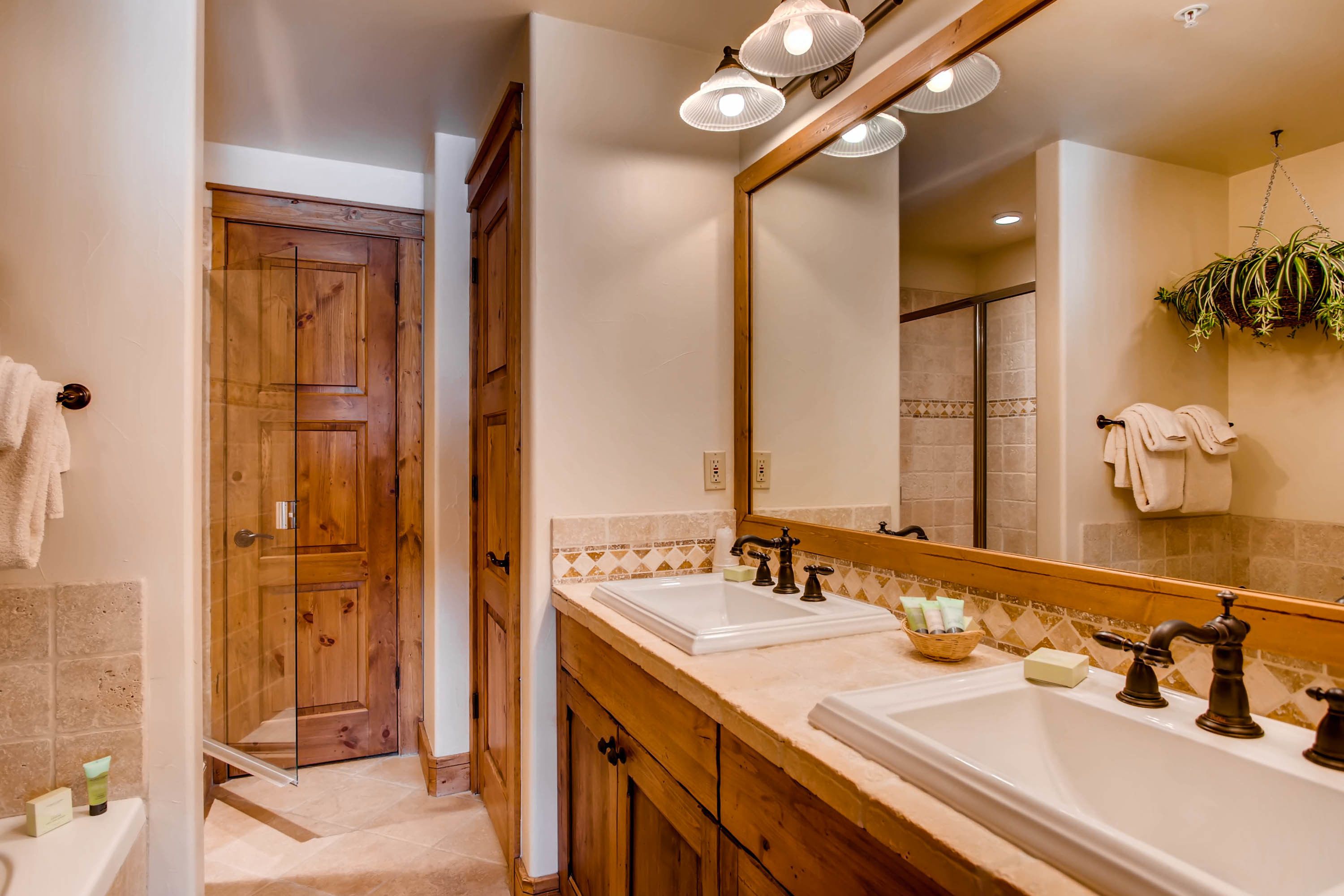 Un baño con muebles de madera, un espejo grande y una zona de ducha.