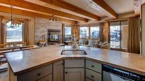 A spacious kitchen with a large island, wooden beams, and a view of the outside.