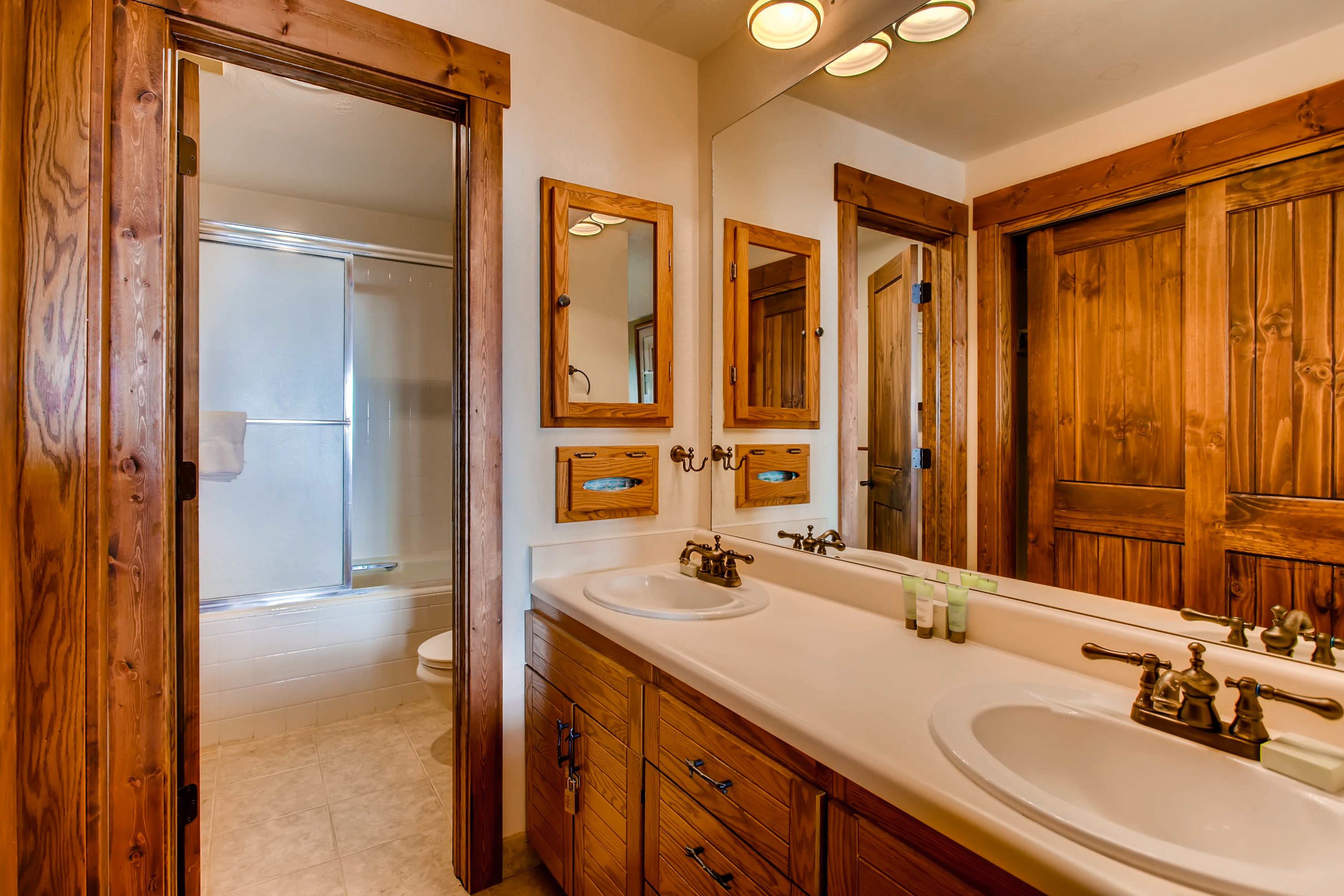 A bathroom with wooden cabinetry, two sinks, and a large mirror.