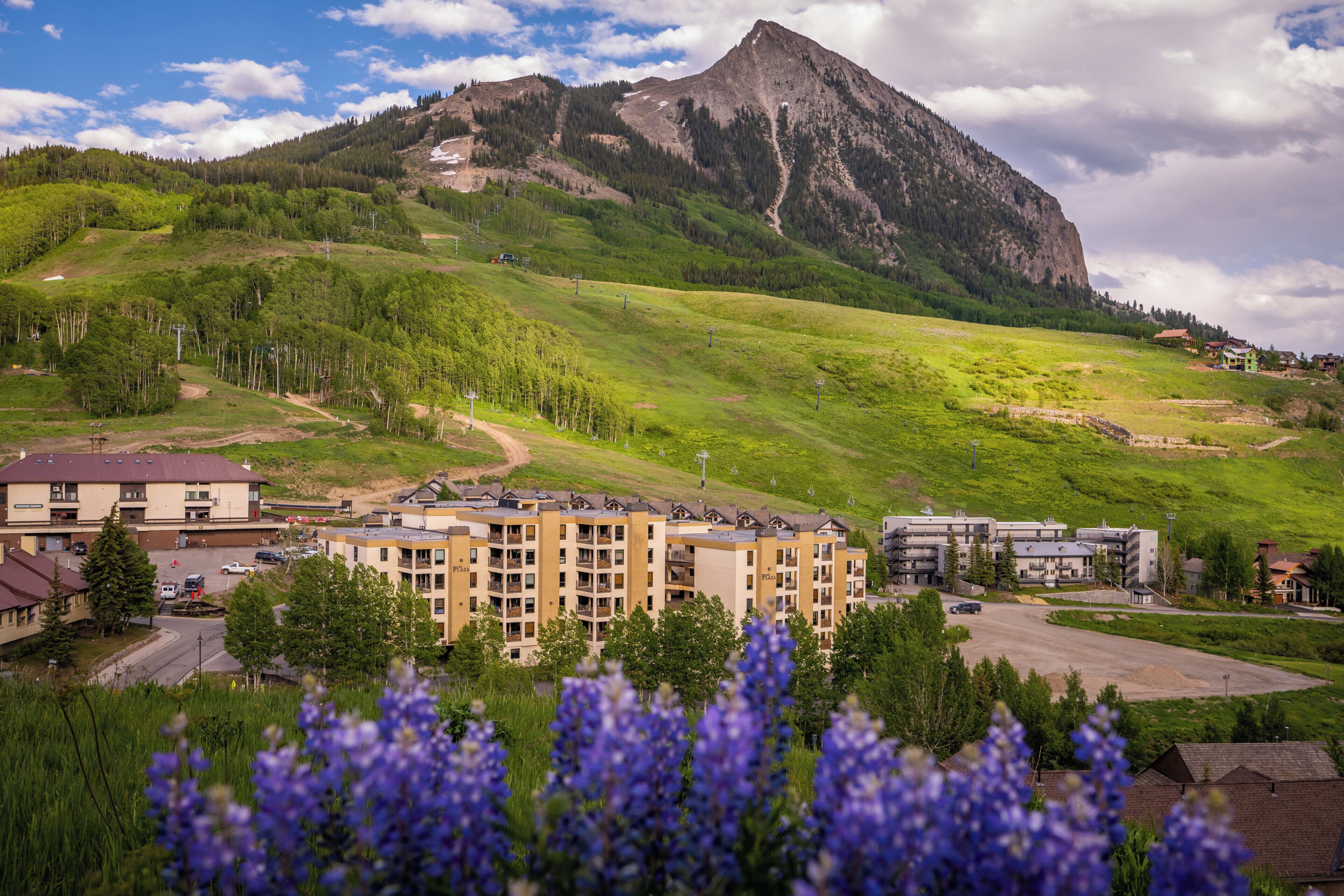 A residential area with a mountain in the background, a parking lot, and buildings with balconies.