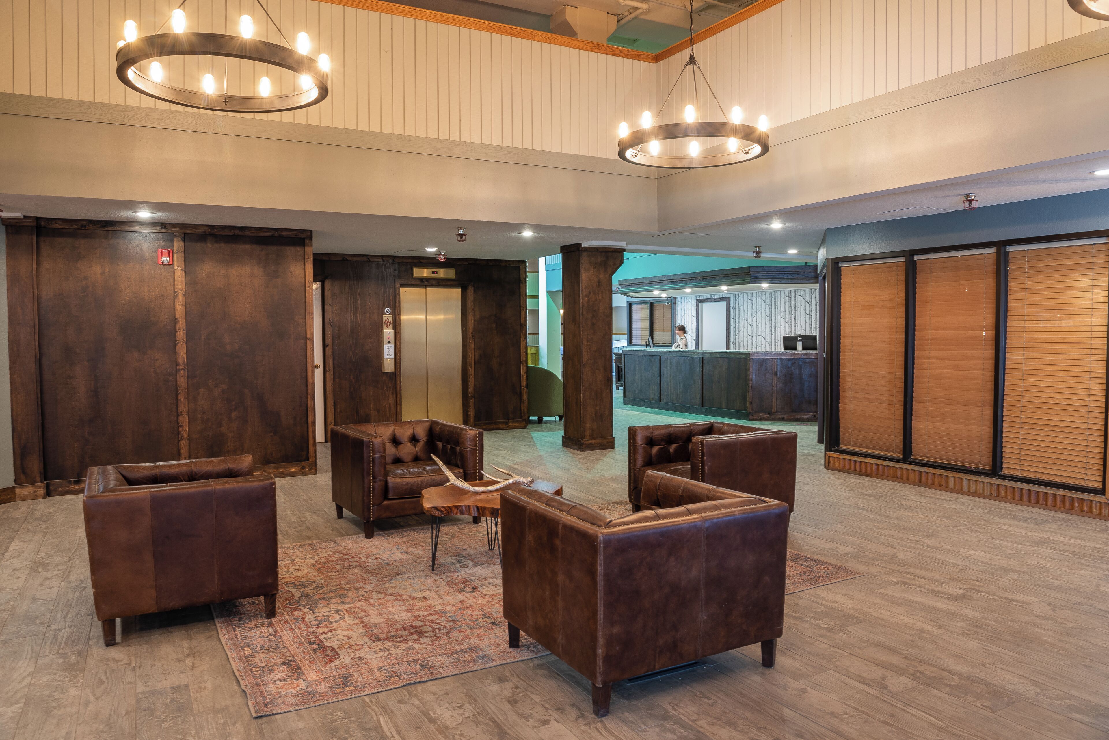 A spacious lobby with leather sofas, a wooden reception desk, and a large wooden door.