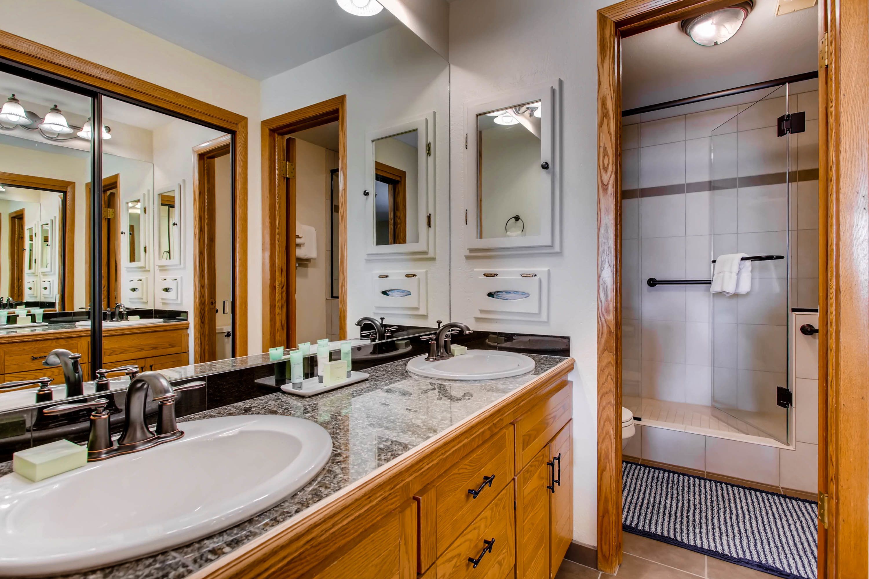 A bathroom with two sinks, a large mirror, and a shower area.
