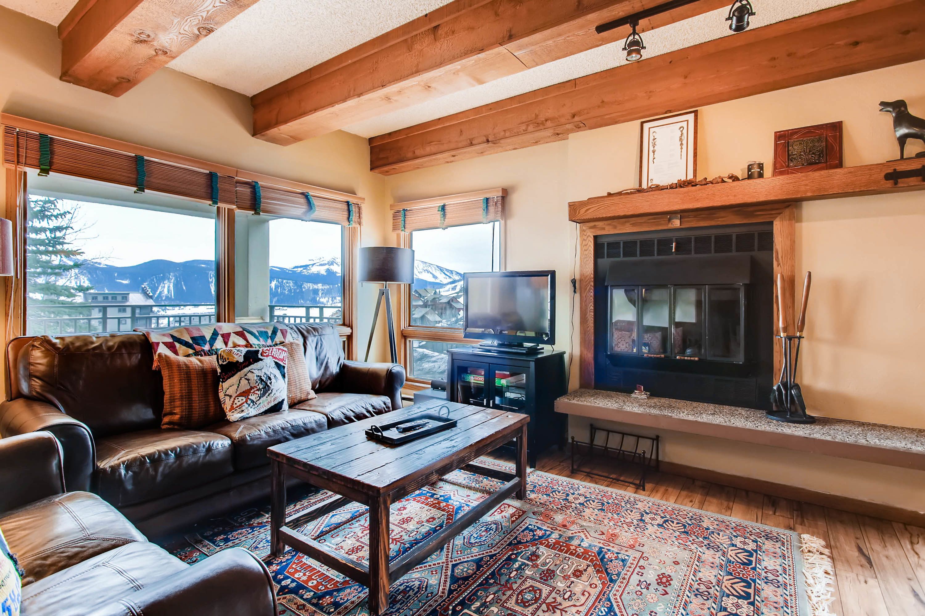 A cozy living room with a leather couch, a wooden coffee table, and a fireplace.