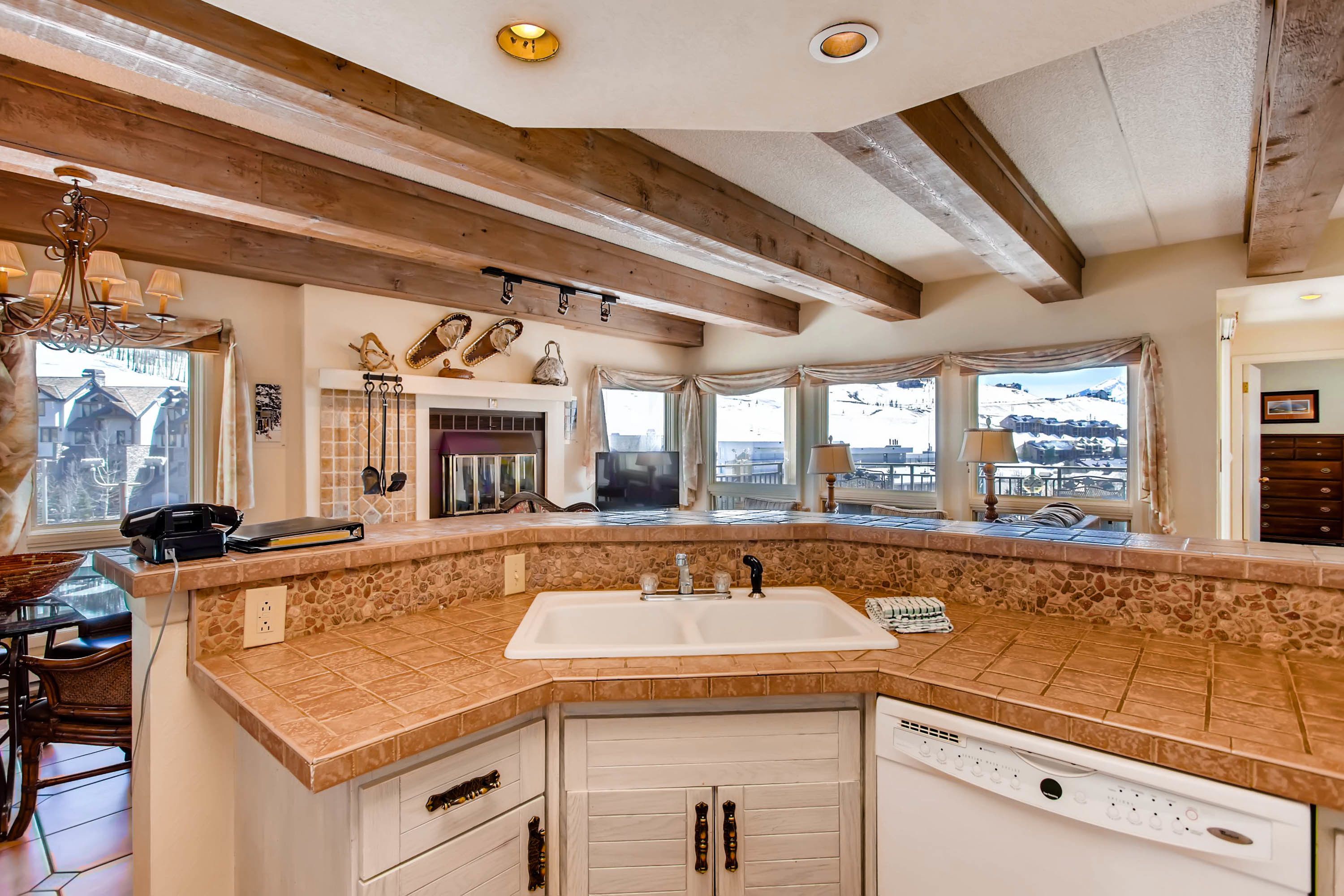A kitchen with a stone countertop, white cabinets, and a built-in dishwasher.