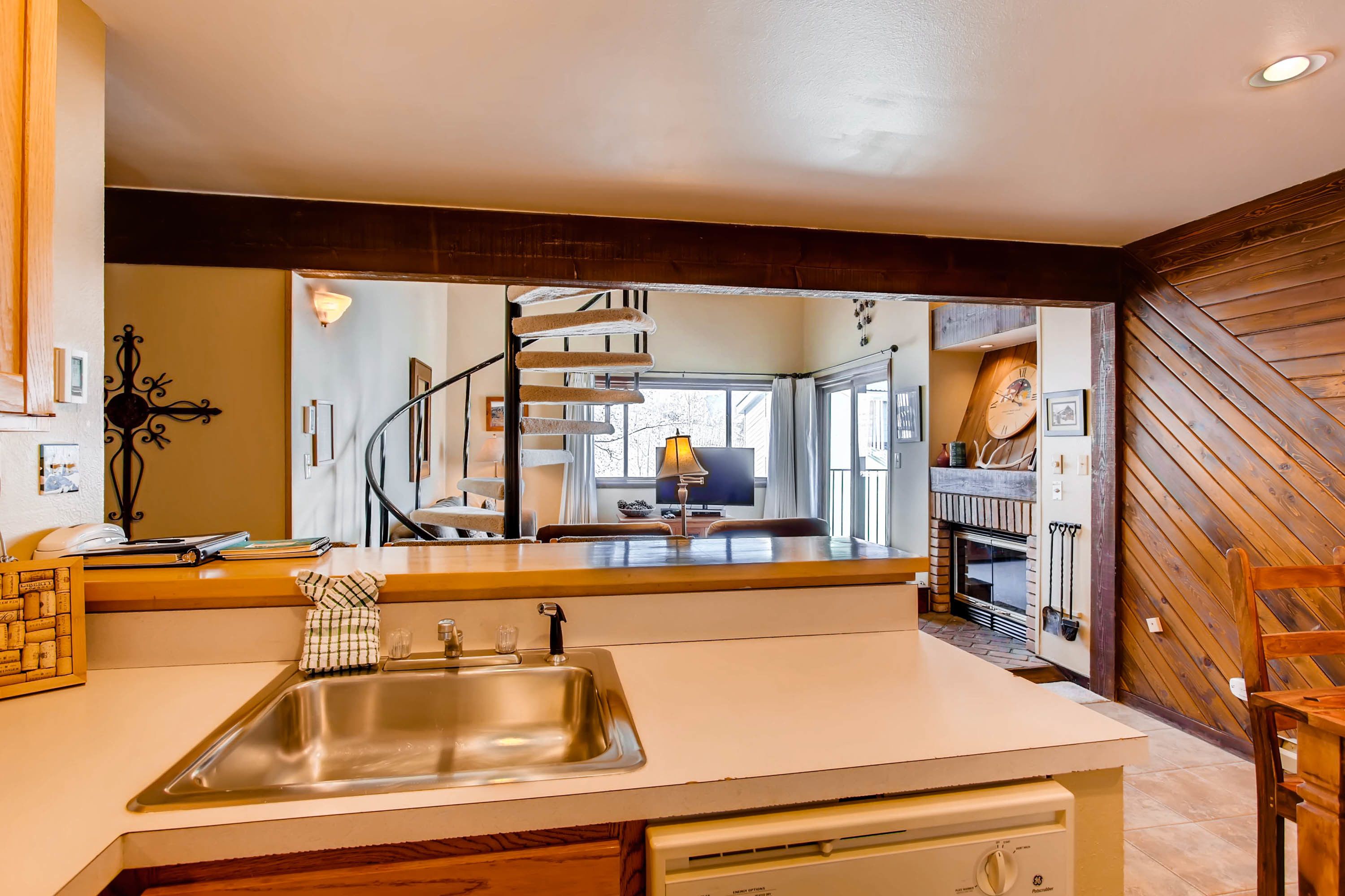 A modern kitchen with a stainless steel sink, wooden cabinets, and a built-in stove.