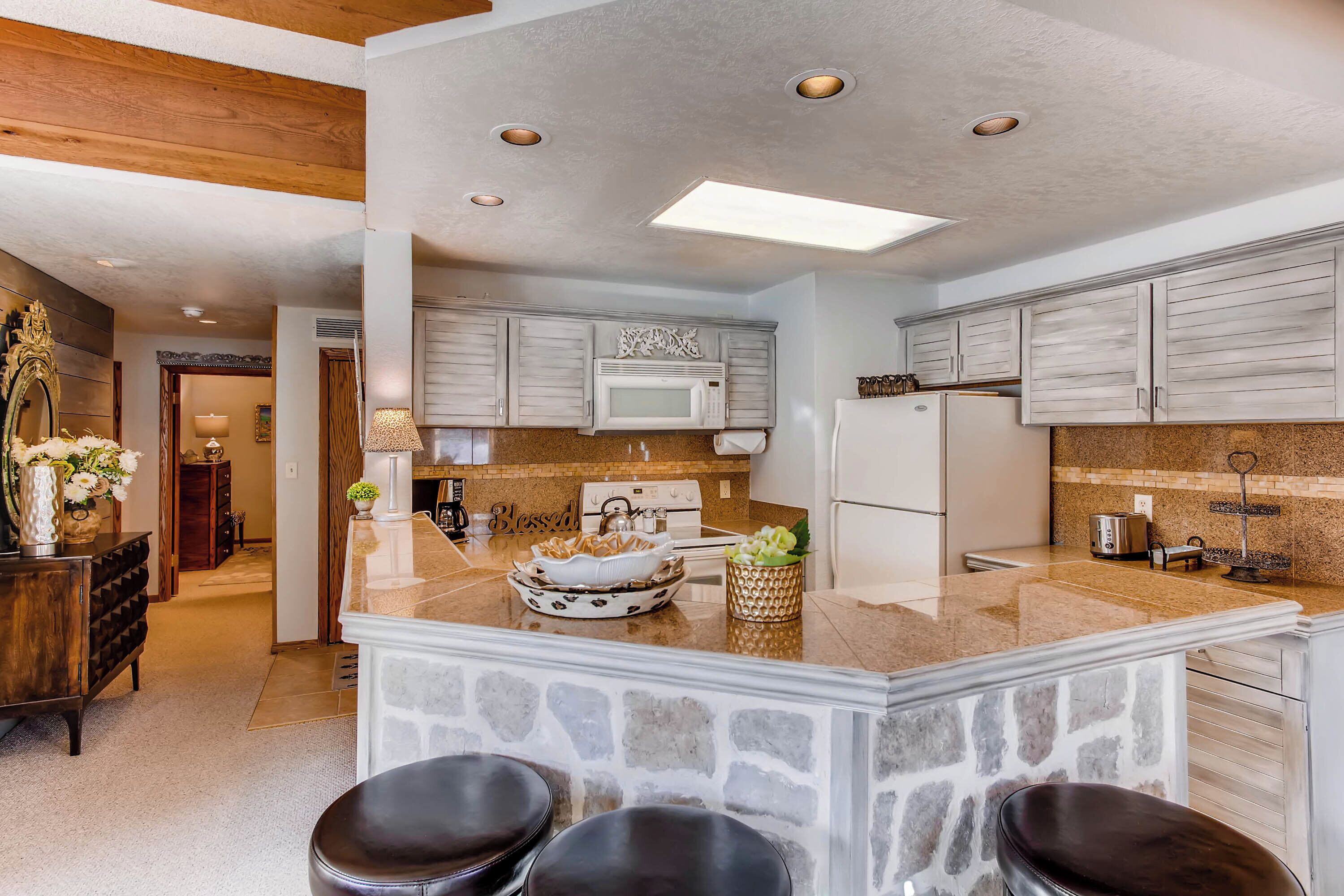 A modern kitchen with granite countertops, white cabinets, and a central island with stools.