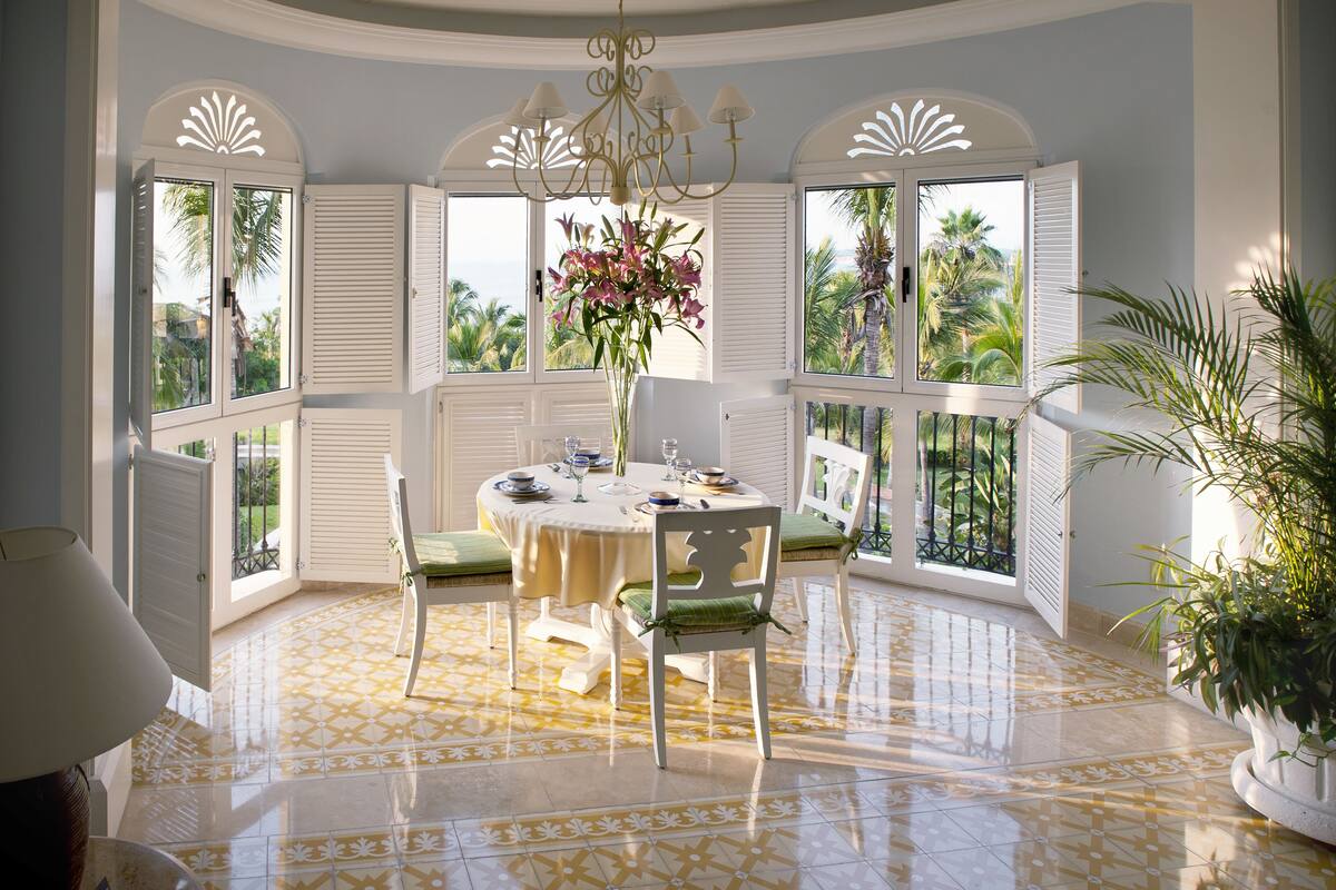 A dining area with a round table, chairs, and a vase of flowers.