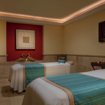 A hotel room with two beds, a red accent wall, and artwork.