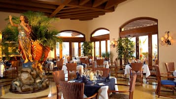 Un restaurante con mesas dispuestas para comer, una estatua y ventanas arqueadas.
