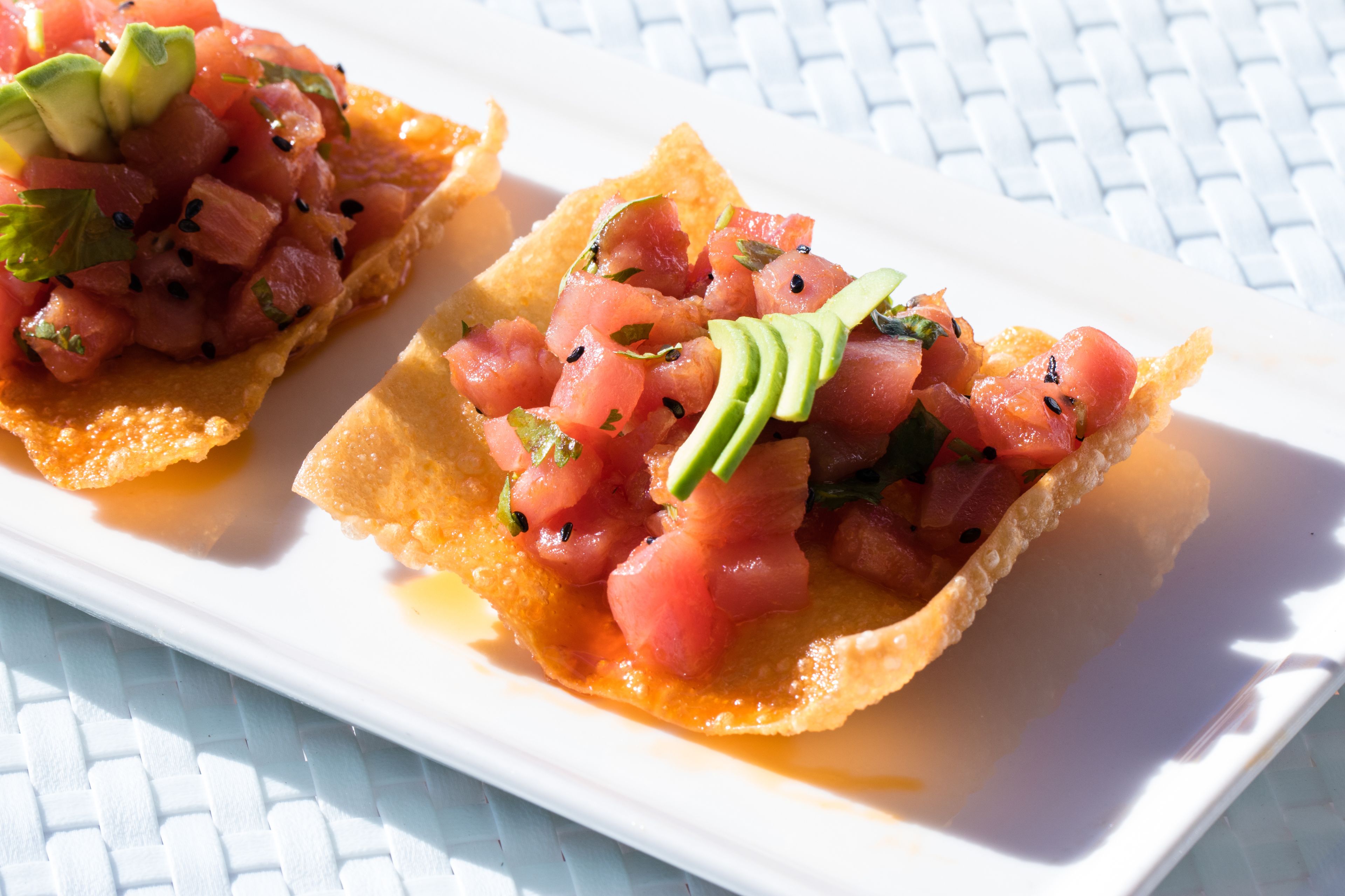 Deux tacos garnis d’avocat et de tomates, présentés sur une assiette blanche.