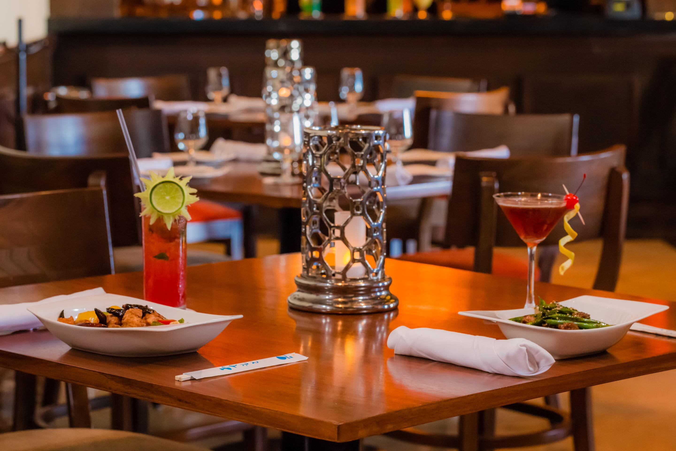 Un restaurant avec des tables dressées pour le service, où l’on peut voir des plats et des boissons.