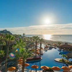 Relax by the pool surrounded by sun loungers and umbrellas, with a scenic ocean view.