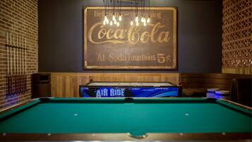 A billiards table with a Coca-Cola sign above it.