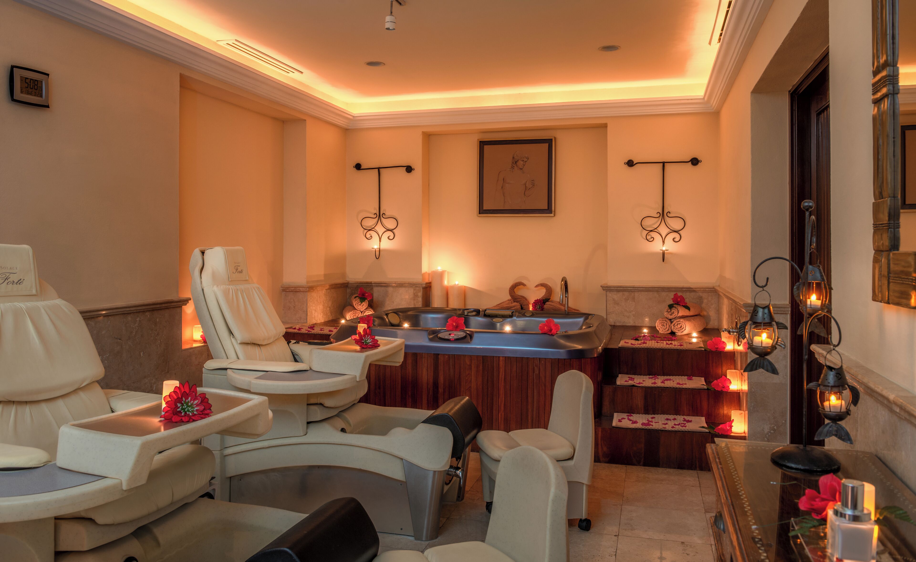Une salle de spa équipée d’un fauteuil de massage, d’un bain à remous et d’une petite table agrémentée de bougies et de fleurs.