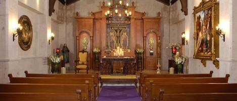 An interior of a church with wooden pews, a purple carpet leading to the altar, and a chandelier.