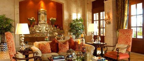 Un interior tradicional con un sofá, sillones, una mesa de centro y objetos decorativos.
