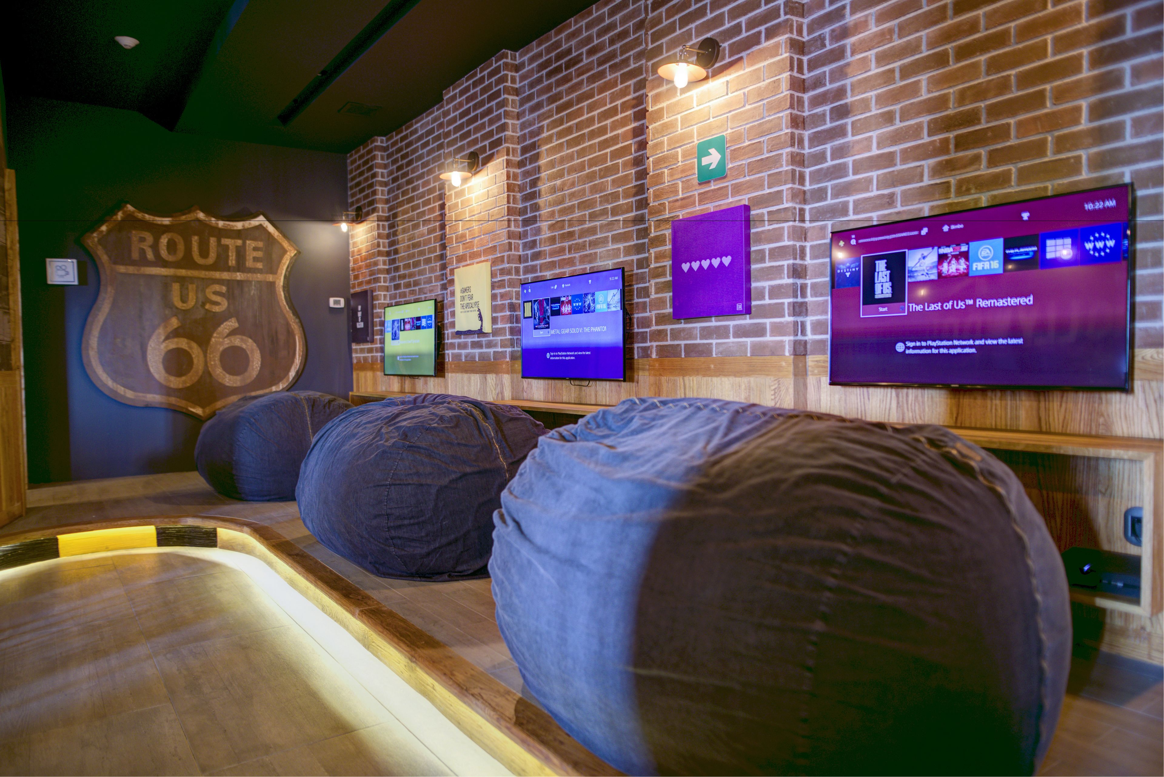 A room with a brick wall, a Route 66 sign, and a television displaying 'The Last of Us Remastered'.