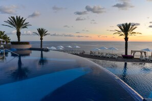 A poolside area with a view of the ocean at sunset, palm trees, and lounge chairs. - Pueblo Bonito Sunset Beach Golf & Spa Resort - All Inclusive (Cabo San Lucas)