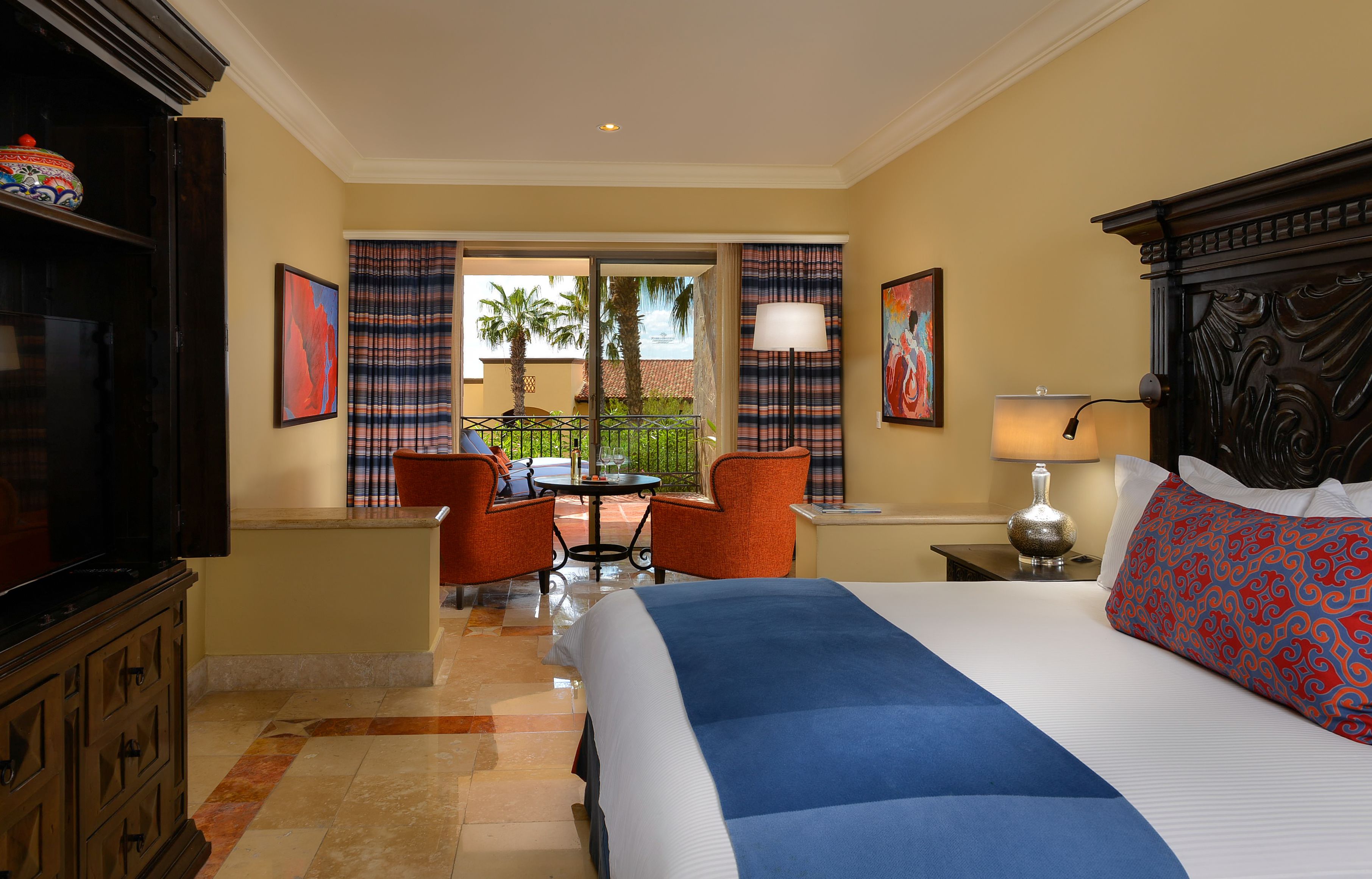 Une chambre d’hôtel avec un grand lit, deux chaises, une petite table et une vue sur l’extérieur.
