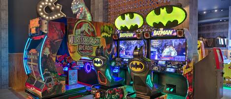 A row of arcade machines with illuminated signs, including "Jurassic Park" and "Batman" themes.