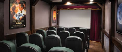A theater with rows of seats, a screen, and a projector.