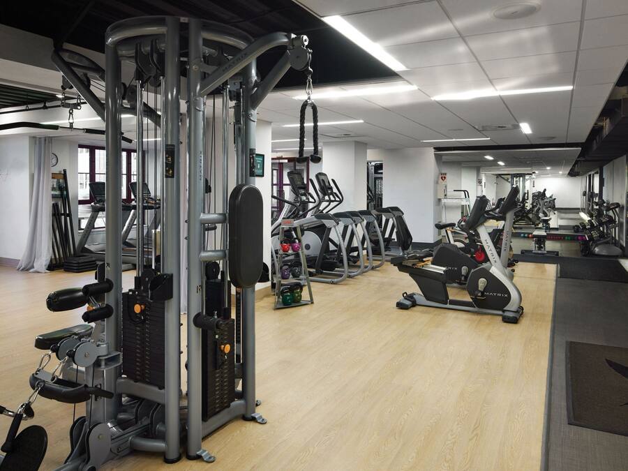 Una palestra con diverse attrezzature per esercizi, tra cui tapis roulant e macchinari per pesi.