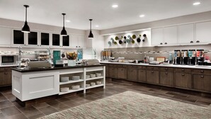 A modern kitchen with white cabinetry, a central island with a sink, and a variety of appliances and utensils.